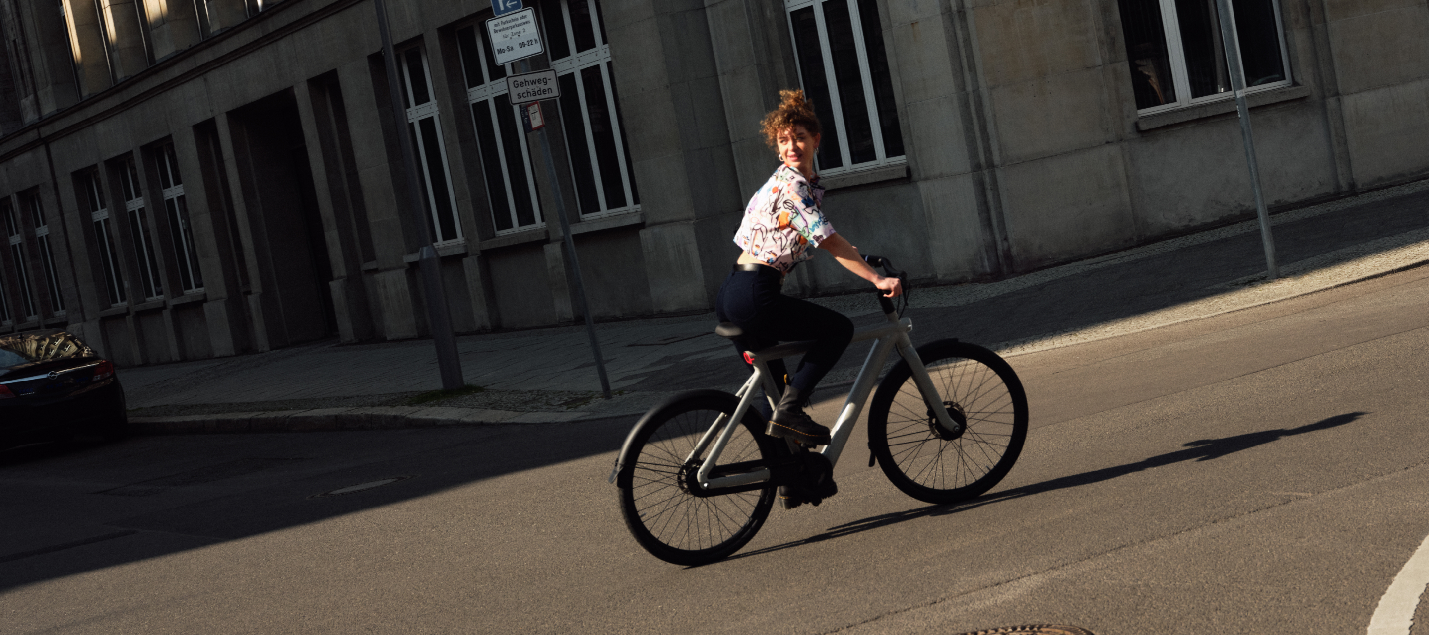 woman riding a vanmoof on an intersection and looking back