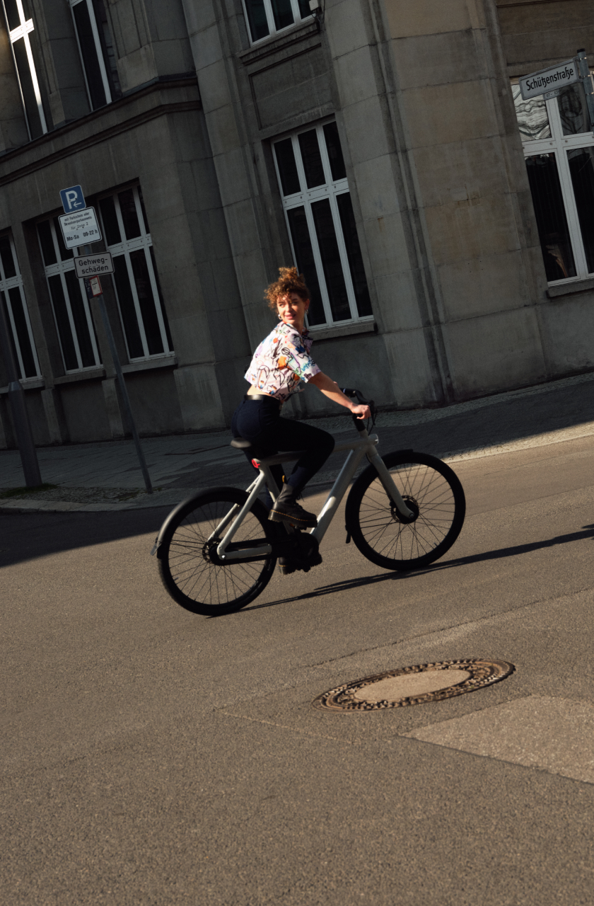 woman riding a vanmoof on an intersection and looking back